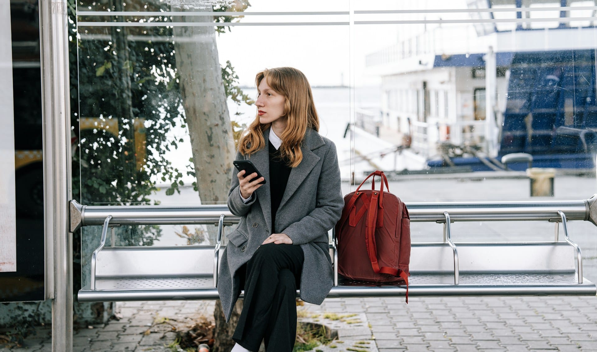 Young expat working on mobile in a sunlit Istanbul bus stop with Bosphorus view